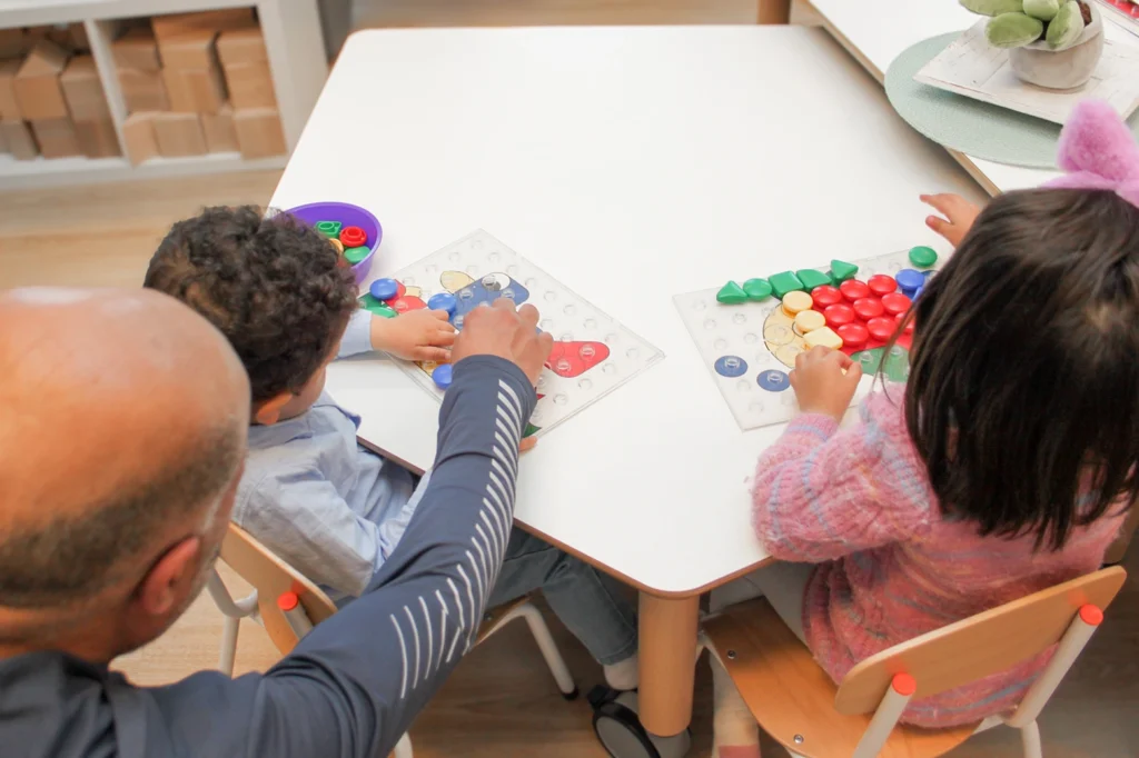 Vrijwilliger helpt twee peuters met puzzel in kleinschalige kinderopvang in Culemborg