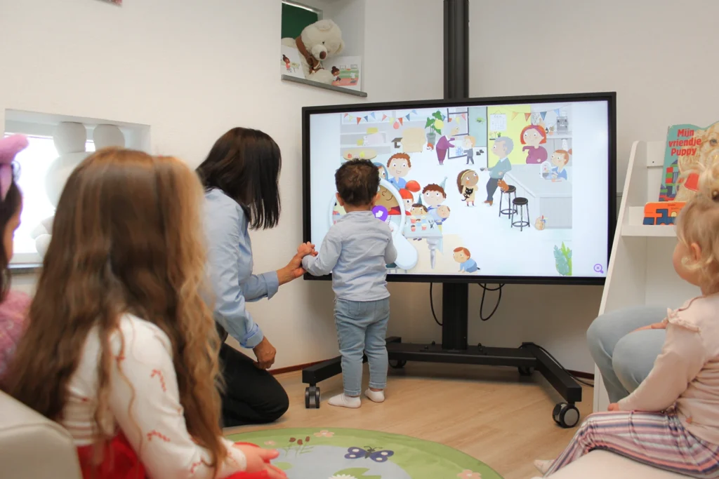 Kinderen doen interactief spel met medewerker op digibord in kinderopvang Culemborg